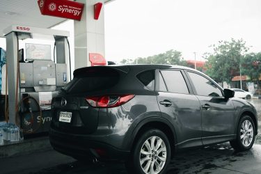 Egy személyautó tankolás közben egy benzinkúton, esős időben.