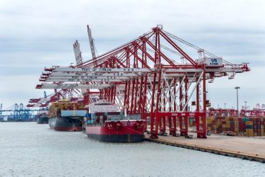 Konténerhajó darukkal felszerelt automatizált tengeri terminálon.