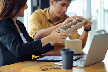 Hallgatók egy innovatív csomagolástervezési megoldást vizsgálnak és értékelnek szakmai környezetben.