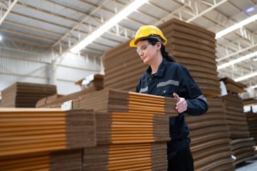 Védősisakos dolgozó kezel papíralapú íveket ipari környezetben, ami jól illusztrálja a csomagolási megfeleléshez kapcsolódó gyakorlati felkészülést.