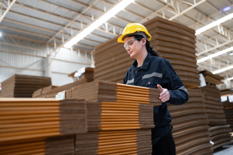 Védősisakos dolgozó kezel papíralapú íveket ipari környezetben, ami jól illusztrálja a csomagolási megfeleléshez kapcsolódó gyakorlati felkészülést.