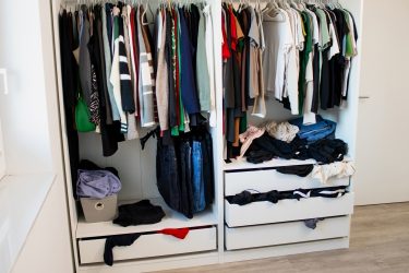 Túlzsúfolt ruhásszekrény sok felhalmozott ruhadarabbal és rendezetlen tárolással.