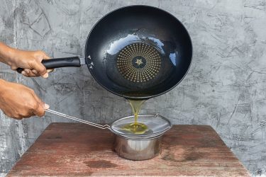 Serpenyőből leszűrt használt étolaj edénybe töltés közben.