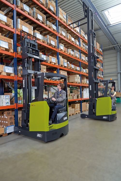 Két Clark raktártechnikai gép dolgozik magas állványrendszerek között raktári környezetben.