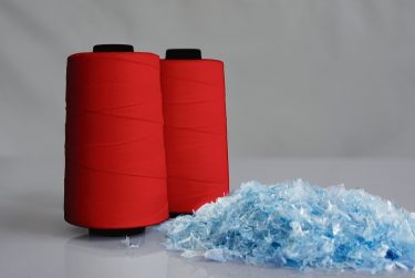 Textilszálak és újrahasznosított alapanyagok láthatók, amelyekből új szövet készülhet.